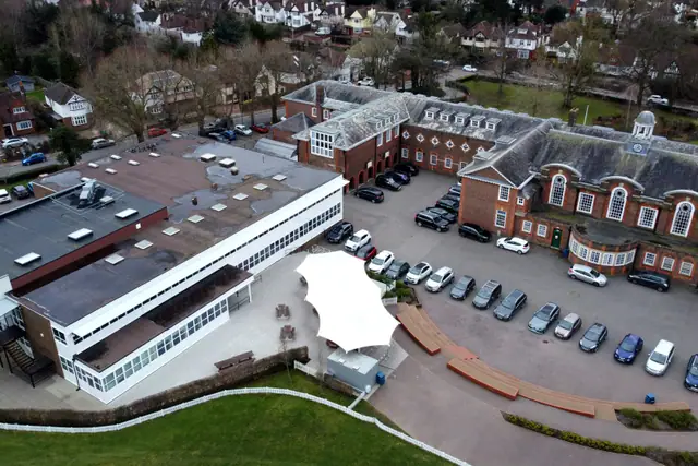 Aerial view of a brick grammar school campus with a car park and playing fields.