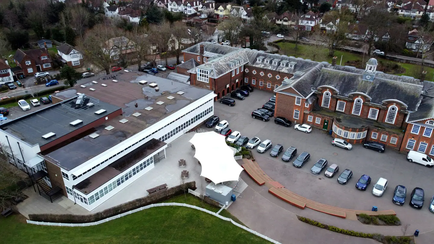 Aerial view of a brick grammar school campus with a car park and playing fields.