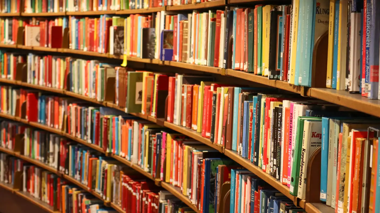 Curved wooden shelves packed with books in a reading room.