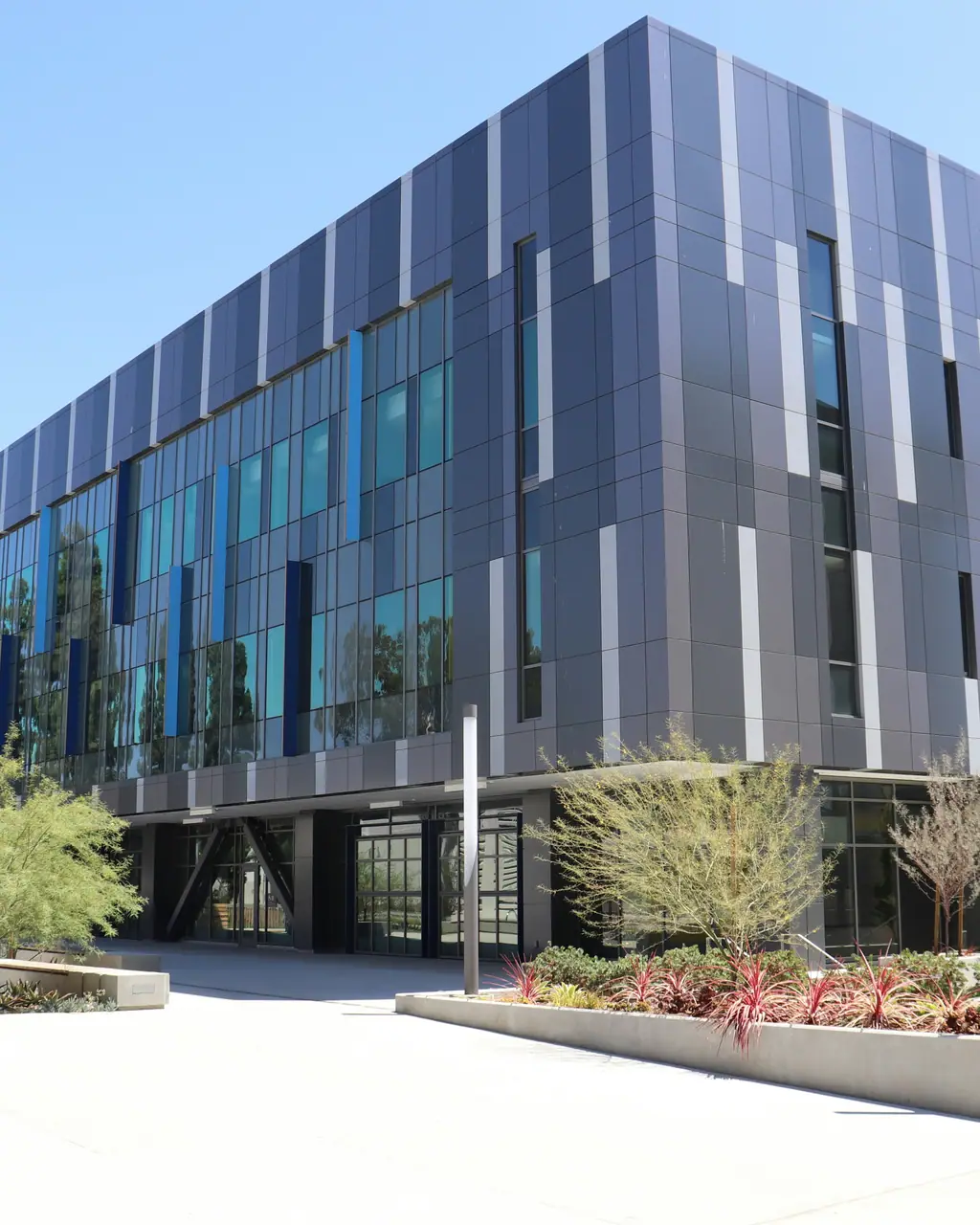 A modern research building clad in glass and dark metal panels.